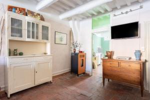 a kitchen with white cabinets and a flat screen tv at Anfiteatro Lucca in Lucca
