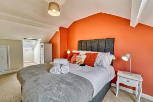 - une chambre avec des murs orange et un grand lit dans l'établissement Guest Homes - Southfield Residence, à Worcester