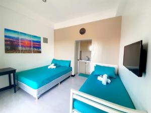 a bedroom with two beds and a tv and a television at Lee Residences by JAL in Legazpi