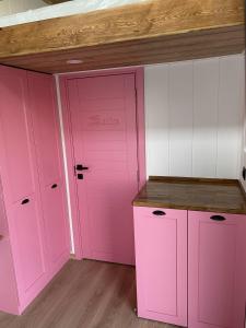 a pink kitchen with white cabinets and a wooden ceiling at Lavira Tiny House Village in Bogazici