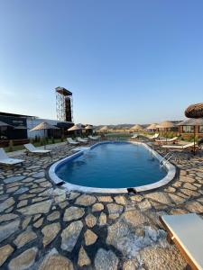 a swimming pool with chairs and a building in the background at Lavira Tiny House Village in Bogazici