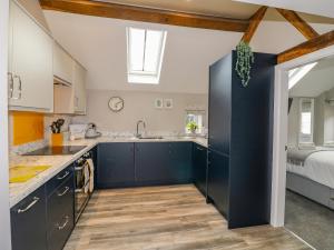 a kitchen with blue cabinets and a bed at The Stables in Whiston