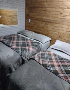 Dos camas en una habitación con paredes de madera. en Casa no centro de Urubici Dutra Borba, en Urubici