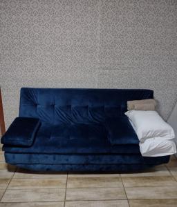 un sofá azul sentado en una habitación con una pared en Casa no centro de Urubici Dutra Borba, en Urubici