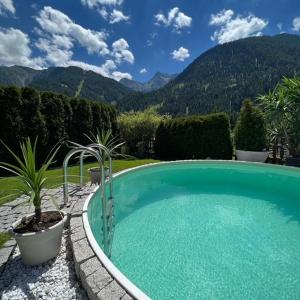 a swimming pool in a garden with mountains in the background at Haus Troger in Sankt Jakob in Defereggen