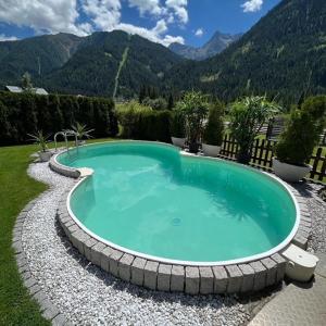 a large swimming pool with rocks around it at Haus Troger in Sankt Jakob in Defereggen