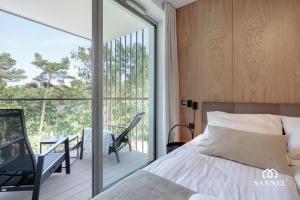 Un dormitorio con una cama y un balcón. en Apartament Baltic Blues z dostępem do basenów,strefy saun,jacuzzi - Pinea Apartments Pobierowo - SANNEL Apartments for rent, en Pobierowo 52 fotos más