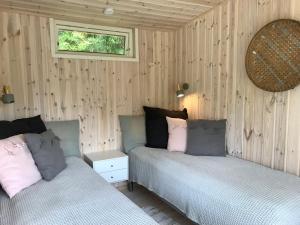 2 Betten in einem Schlafzimmer mit Holzwänden und einem Fenster in der Unterkunft Backahusets B&B in Höör