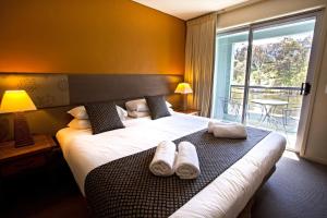 Novotel Lake Crackenback Resort في كراكينباك: غرفة فندق عليها سرير وفوط