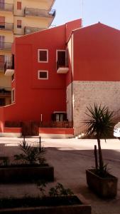 un edificio rojo con plantas delante de él en La Casa di Petra, en Módica