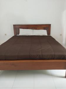 a bed with a wooden frame with a brown blanket at Lombok Collection Gili Air in Gili Islands