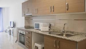 La cuisine est équipée d'un évier et d'un four micro-ondes. dans l'établissement Apartamentos Boutique Benicasim, à Benicàssim