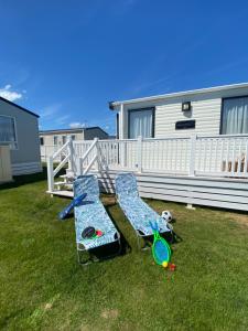 two lawn chairs and a dog sitting in a yard at Winchelsea Beach Holiday Home - Pool & Beach in Winchelsea