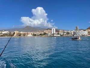 a boat in the water with a city in the background at Achacay Sunset Apartment in Los Cristianos