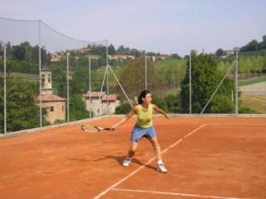 una donna che tiene una racchetta da tennis su un campo da tennis di Ca' Villa Club Agriturismo a Gabiano