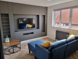 uma sala de estar com um sofá azul e uma televisão em Holiday Apartment Beverley em Beverley