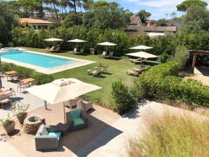 uma piscina com cadeiras e guarda-sóis ao lado de um quintal em Arli Hotel Hideaway Punta Ala - Adults Only em Punta Ala