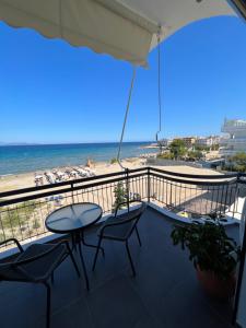 a balcony with a table and chairs and the beach at Lookis Sea view Near Airport in Artemida