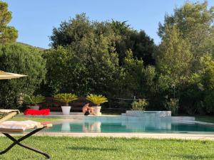 un uomo seduto accanto a una piscina di Arli Hotel Hideaway Punta Ala - Adults Only a Punta Ala