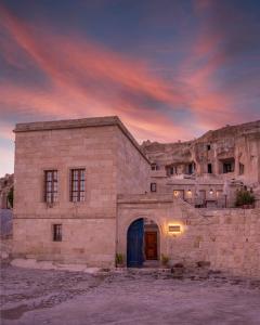 ein altes Steingebäude mit blauer Tür bei Sonnenuntergang in der Unterkunft Serinn House in Ürgüp