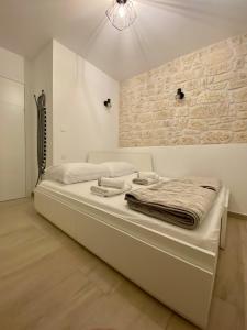 ein weißes Bett in einem Zimmer mit Ziegelwand in der Unterkunft Citadela in Primošten