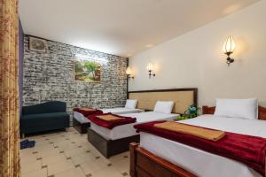 um quarto de hotel com três camas e uma cadeira em Hanoisunflowersuitehostel em Hanói