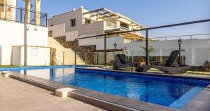a swimming pool with two chairs in front of a building at סוויטות אושר בגולן in Had Nes