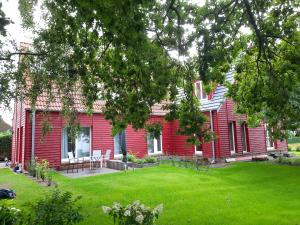 uma casa vermelha com um relvado à frente em Ferienwohnung Rote Kate em Born