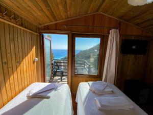 two beds in a room with a view of the ocean at Tree Houses Hotel in Fethiye