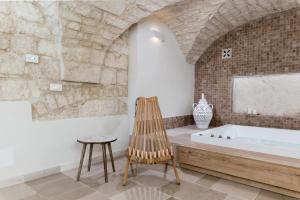 y baño con bañera y silla de madera. en Alba Luxury Suite, en Ostuni
