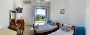 a room with two beds and a television and a window at Philoxeni Akti in Kanali