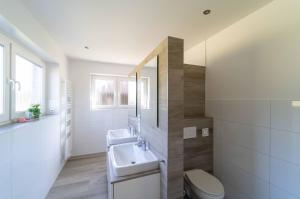 ein weißes Badezimmer mit Waschbecken und Toilette in der Unterkunft Seevilla am See mit Sauna, Kamin, privatem Steg und Seezugang in Barßel