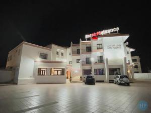 un gran edificio blanco con aparcamiento por la noche en Hôtel Plaisance en Meknès