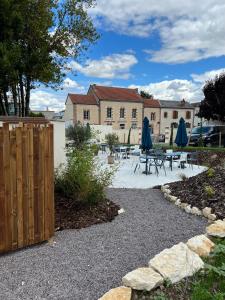 a patio with tables and blue umbrellas in front of a building at Best Western Le Relais du Vigneron in Vertus