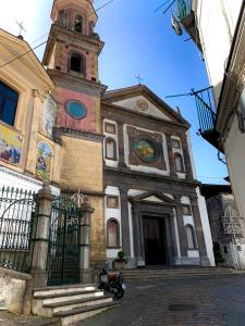 een kerk met een klokkentoren en een motor geparkeerd voor de deur bij La Finestra sul Duomo, Amalfi Coast in Vietri