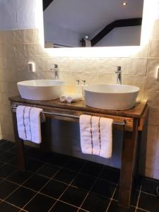 a bathroom with two sinks and a mirror and towels at De Beijersche Stee , Landhuysje in Stolwijk