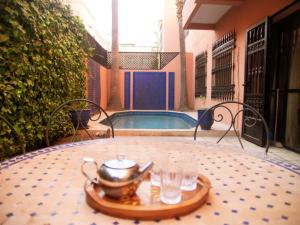 Villa Sabah في مراكش: طاولة عليها وعاء للشاي وكؤوس