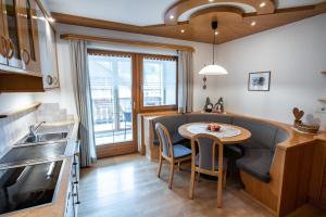 een keuken met een tafel met stoelen en een wastafel bij Apartment ARGENTIS Krumas-Living - Kronplatz in San Vigilio Di Marebbe