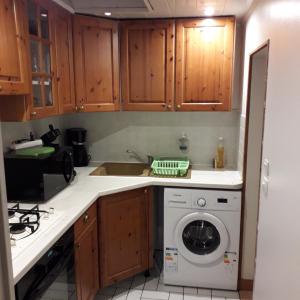 a kitchen with wooden cabinets and a washing machine at petite maison plain pied proche dunkerque in Boomkens
