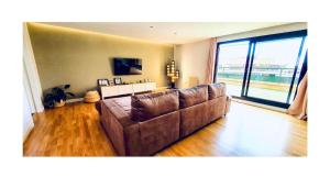 a brown couch in a living room with a large window at Lovely penthouse condo with pool in Valencia