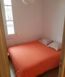 - un lit orange dans une chambre avec fenêtre dans l'établissement A 2 PAS DU PARLEMENT - 55M2 - 2 CHAMBRES, à Rennes
