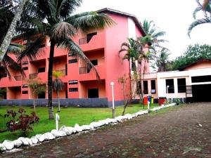 un edificio rosa con palmeras delante en Ilha Morena Praia Hotel, en Caraguatatuba
