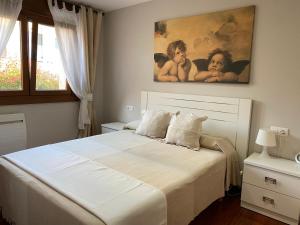 a bedroom with a white bed with a painting on the wall at Mar y Sol in Sanxenxo
