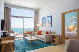 a living room with a couch and a bedroom at Centara Mirage Beach Resort Dubai in Dubai