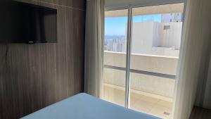 a bedroom with a bed and a large window at Flat Brookfield Towers 2414 in Goiânia