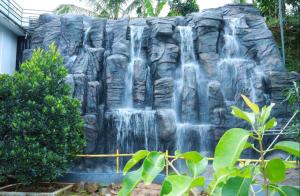 uma cascata em frente a uma parede de pedra em Emerald Royal Residency em Cochin