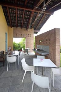 a patio with white tables and chairs and a brick wall at A Casa di Maria in Grinzane Cavour