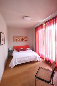 a bedroom with a white bed and red curtains at A Casa di Maria in Grinzane Cavour