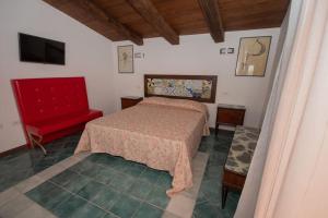 a bedroom with a bed and a red chair at Palazzo Santa Maria - Fondazione Meeting del Mare C.R.E.A. in Camerota