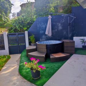 a backyard with a hot tub and wicker chairs and flowers at les tiny houses d'akapa in Sainte-Luce